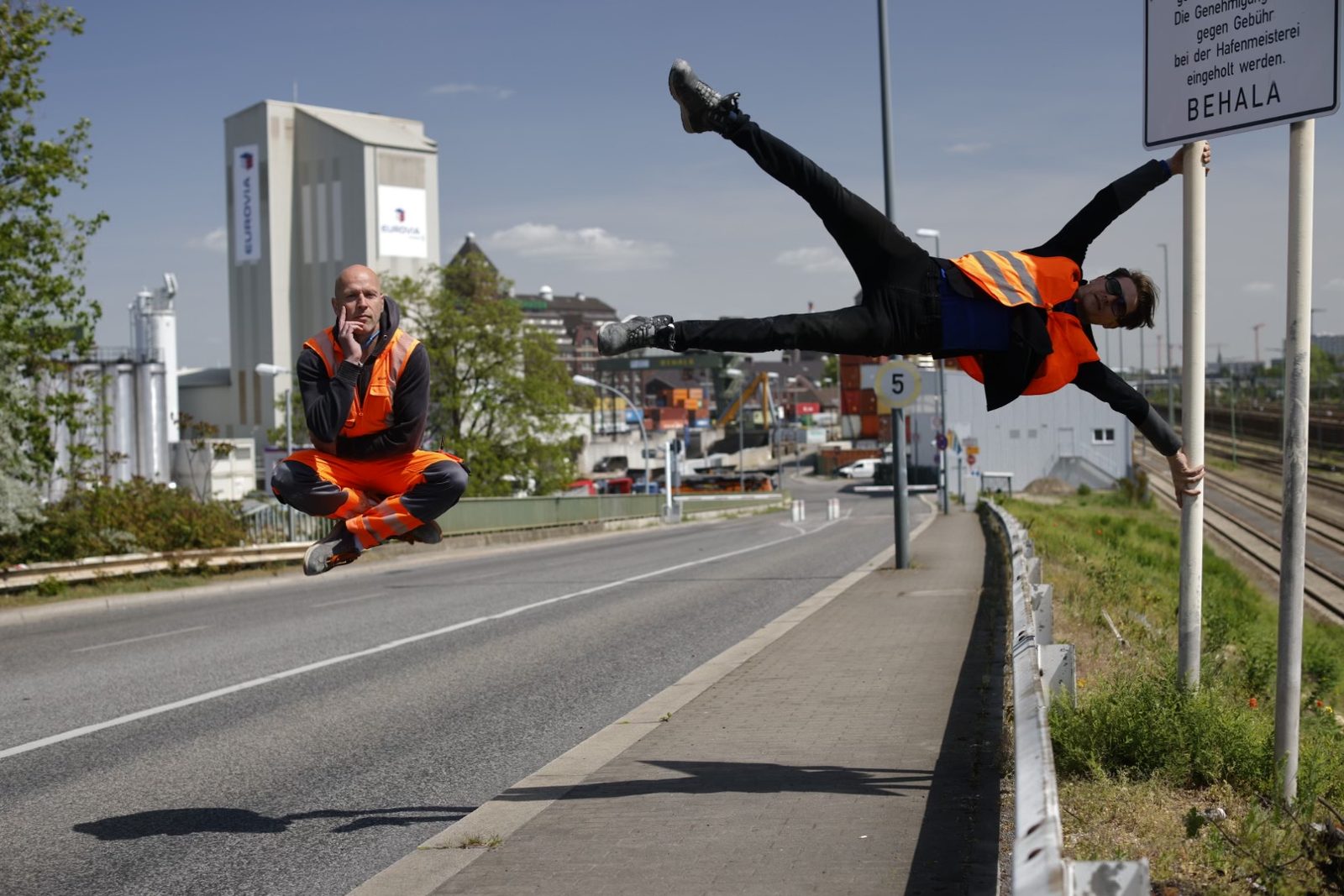Freie Fotokunst, 100% real ohne Bildbearbeitung: Dirk Mathesius in schwebender Hocke und John Förster als Human-Flag am BEHALA-Schild, Berliner Westhafen