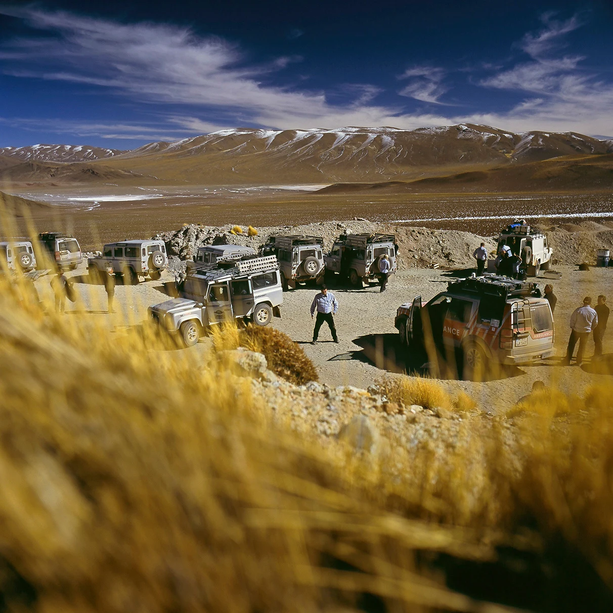 Eine Geländewagen Kolonne rastet vor karger und teiweise gefrorener Berglandschaft in Argentinien während einer Land Rover Experience Tour; aufgenommen für Mens Health Magazin mit Hasselblad 501c FarbDia-Film.