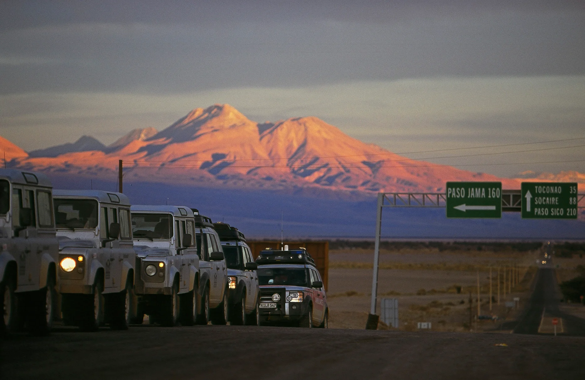 Eine wartende Geländewagen Kolonne und Berglandschaft im Hintergrund in Argentinien während einer Land Rover Experience Tour, aufgenommen für Mens Health Magazin mit FarbDia-Film.