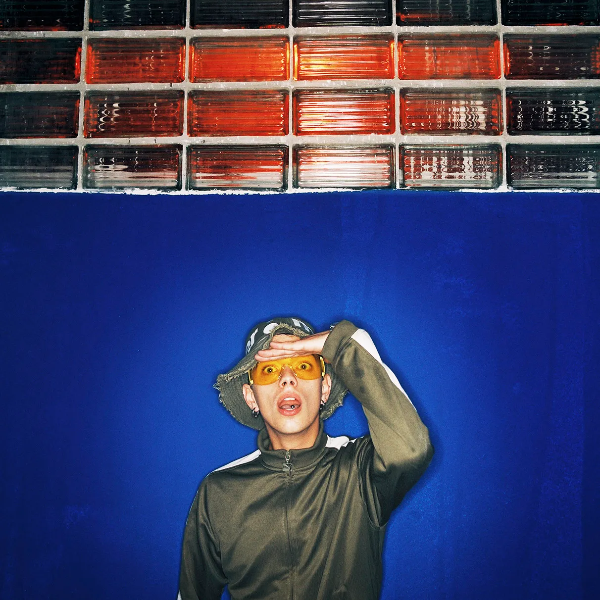 Der DJ Housemeister posiert vor einer farbigen Glasziegelwand in der damaligen Techno-location bittersweet in der Papierfabrik in Burg Stargard, aufgenommen mit Hasselblad 501c FarbNegativ-Film