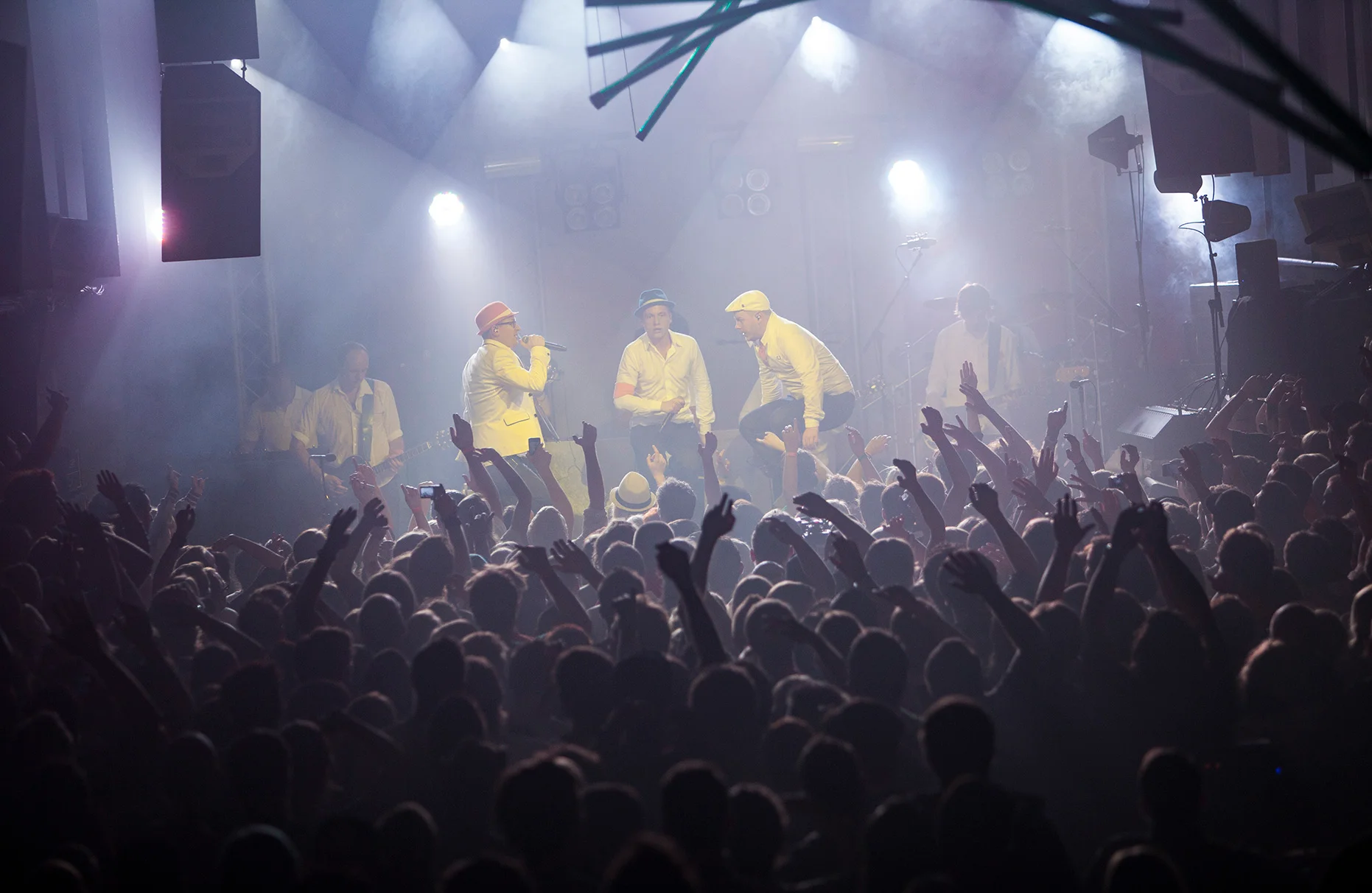 Die Band Fettes Brot singt und springt auf der Bühne während eines Konzertes in Amsterdam. Im Vordergrund jubelt und feiert das Publikum. Das Konzert wurde von Red Bull veranstaltet. Der Veranstaltungsort Amsterdam bezog sich auf den seinerzeit gleichnamigen song.
