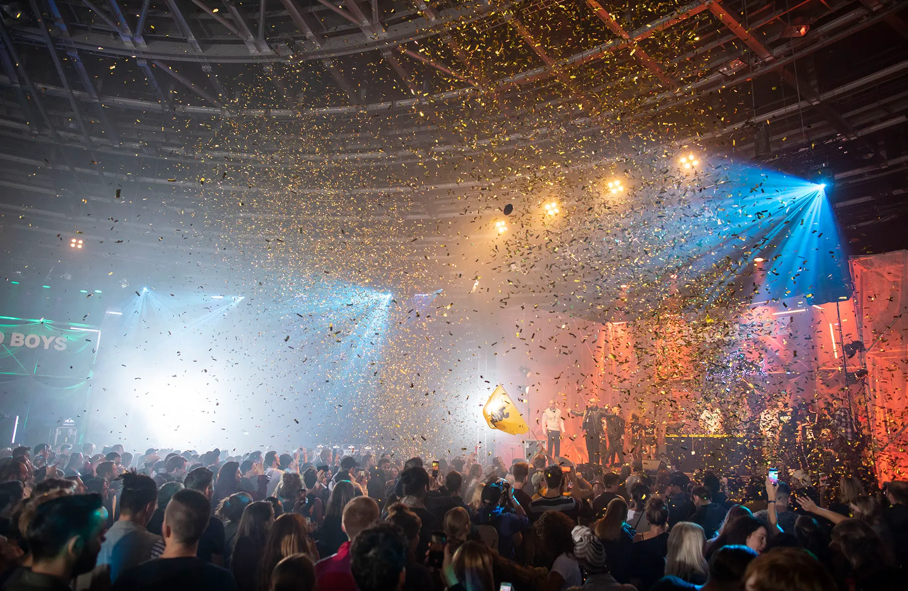 Zwei bespielte Bühnen der eigentlich vier Bühnen eines Red Bull culture clash mit farbiger Beleuchtung aus Laser, Nebel und Gegenlicht. Es regnet Gold- Konfetti. Die Veranstaltung fand im Berliner Velodrom statt.