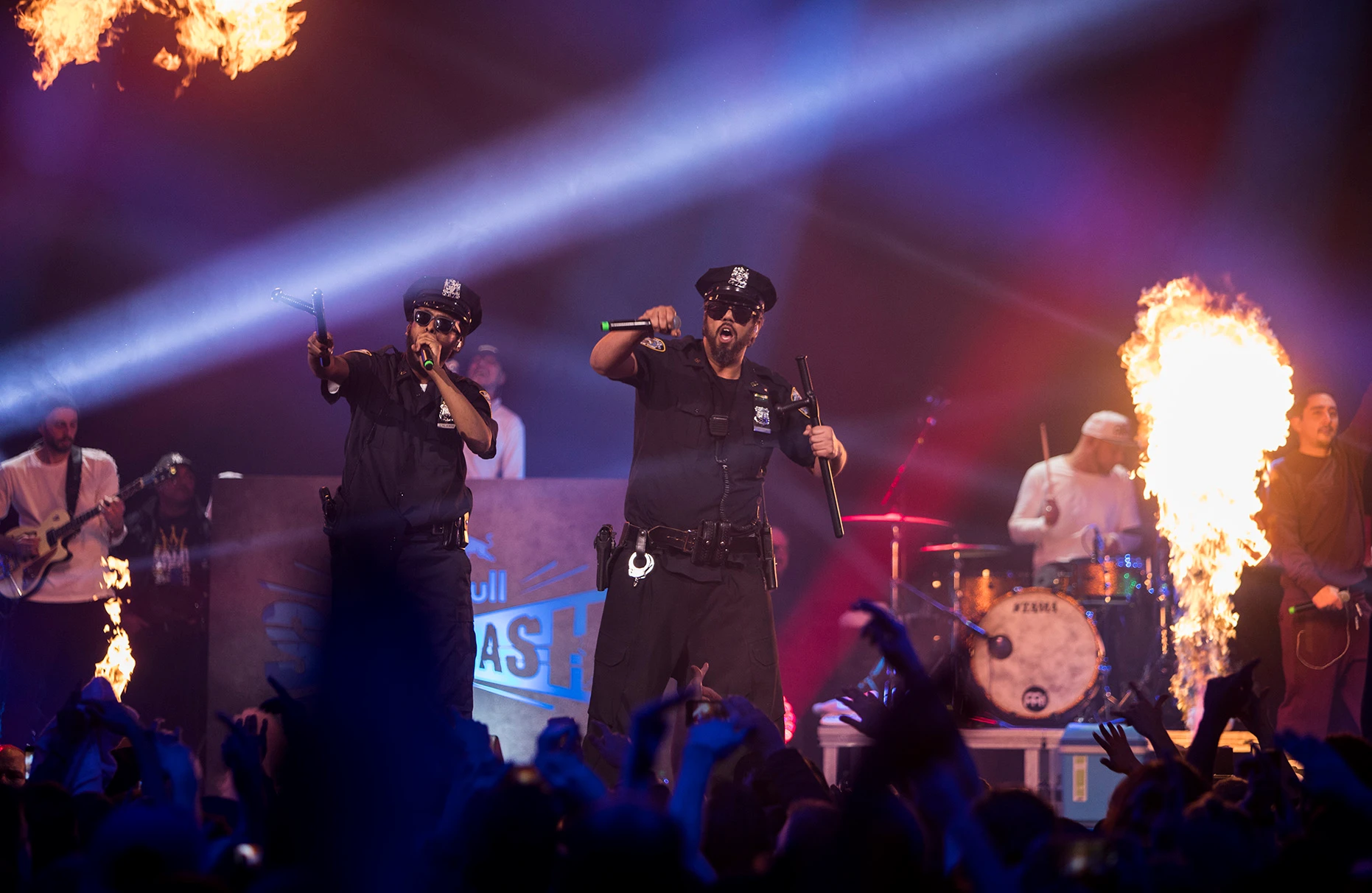 Die Künstler Sammy Deluxe und Afrob singen während des Red Bull sound clash in Hamburg vor Publikum. . Es spielen und singen bei diesem sound clash CRACK IGNAZ, LGOONY, SOUFIAN vom Team New Level gegen SAMY DELUXE, EKO FRESH, AFROB vom Team Reality Check. Die Beiden tragen amerikanische Polzeiuniformen und auf der Bühne spuckt die Pyrotechnik Feuerstösse.