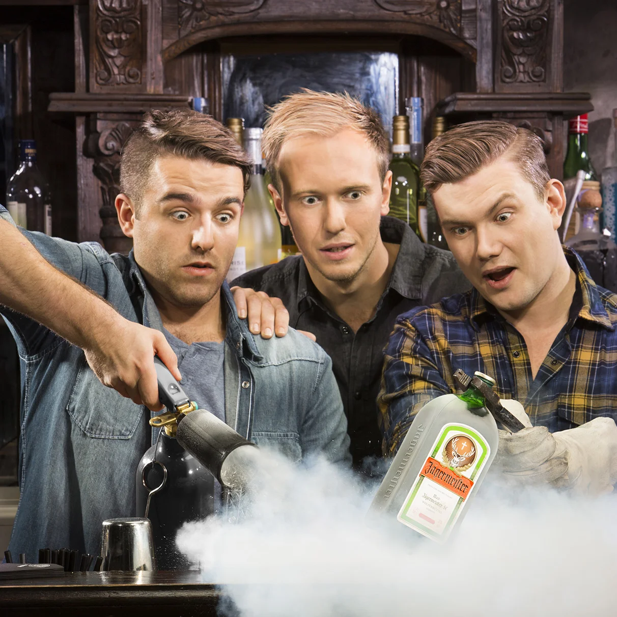 Drei junge Männer in einer altmodischen holzigen Bar versuchen eine Jägermeister Flasche auf dem Tresen mit einem CO2 Löscher zu kühlen und staunen mit aufgerissenen Augen. Produziert anlässlich einer Jägermeister PR Kampagne für Schröder & Schömbs PR.