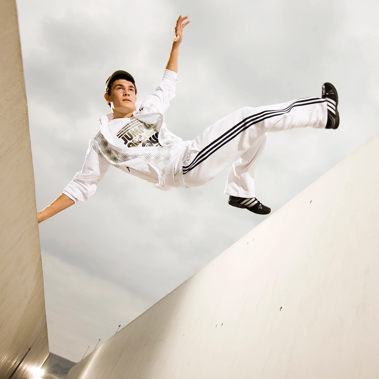 Der Akrobat und freerunner John Förtsre springt einen coolen stunt in einerm weissen Betongang am Velodrom Berlin in sportlichem Adidas outfit. Prodziert für das adidas global lookbook/ Men's Training Spring Summer.