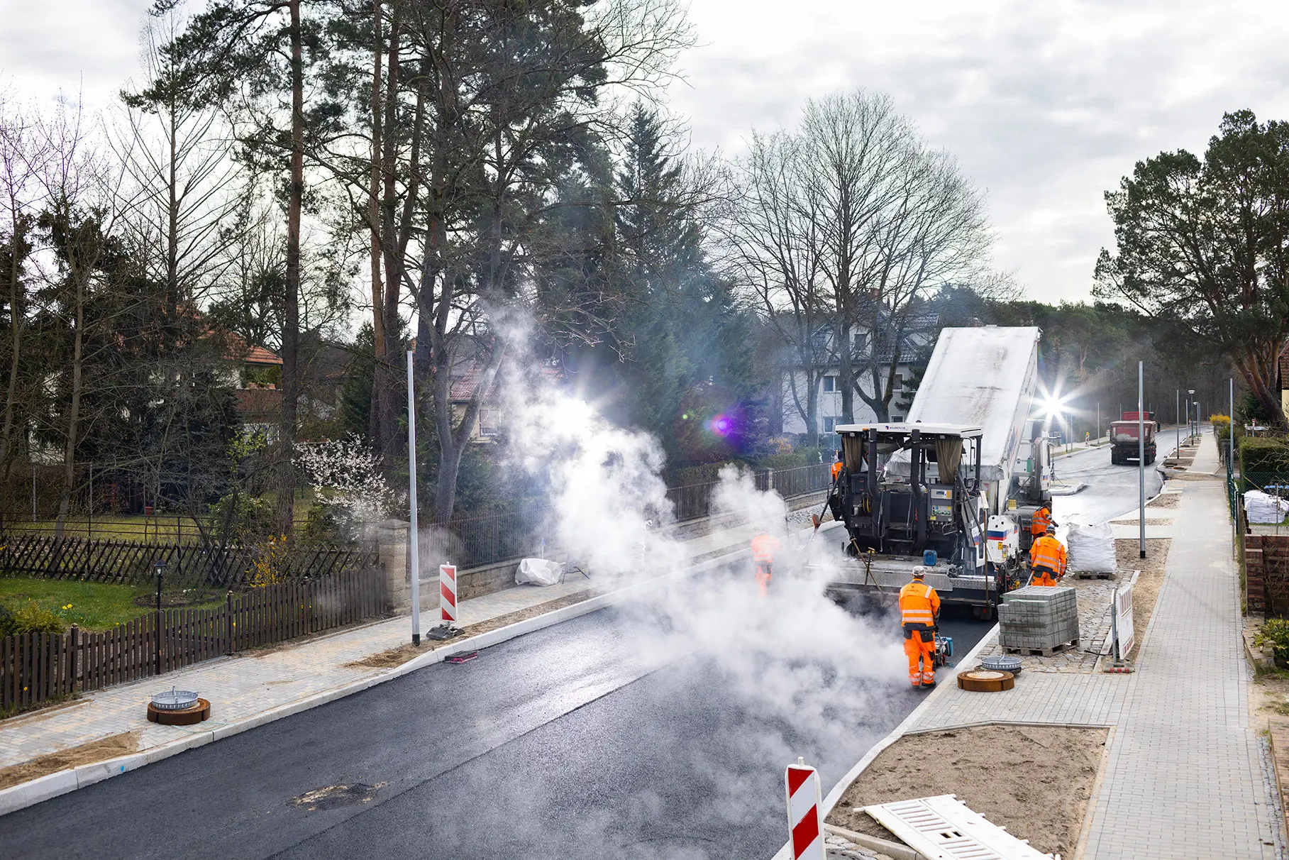 Eine Baustelle in einer Kleinstadt. Es wird eine Asphalt- Fahrbahn mit Fertiger saniert. Die Strasse in der Flucht leicht von oben fotografiert mit natürlichen Nebel des heissen Teer's und künstlichem Gegenlicht durch aufgestellte mobile Blitzköpfe. Produziert für Eurovia Niederlassung Lindow.