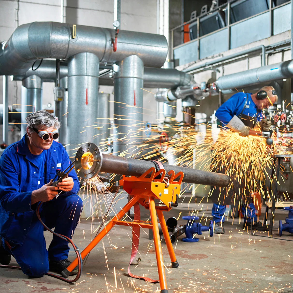 Zwei Arbeiter im Blaumann schweissen mit Schutzbrille in einer Werkstatt an einem Metall- Rohr. Produziert für eine Image- Kampagne der Stadtwerke Torgelow mit Hasselblad 501c CFV 16.