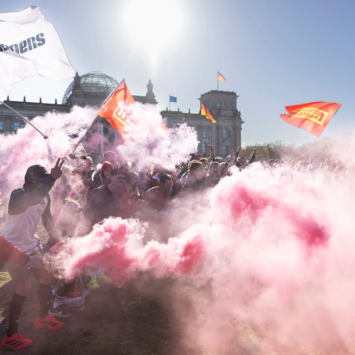 Vor dem Berliner Reichstag zelebriert eine grössere Teilnehmer- Gruppe das warm up vor dem Halbmarathon- Lauf. Entzündete Rauchfackeln und schwingende Fahnen sorgen für eine action- Film ähnliche Szenerie. Aufgenommen für SCC Berlin, der Veranstalter des Halbmarathon.