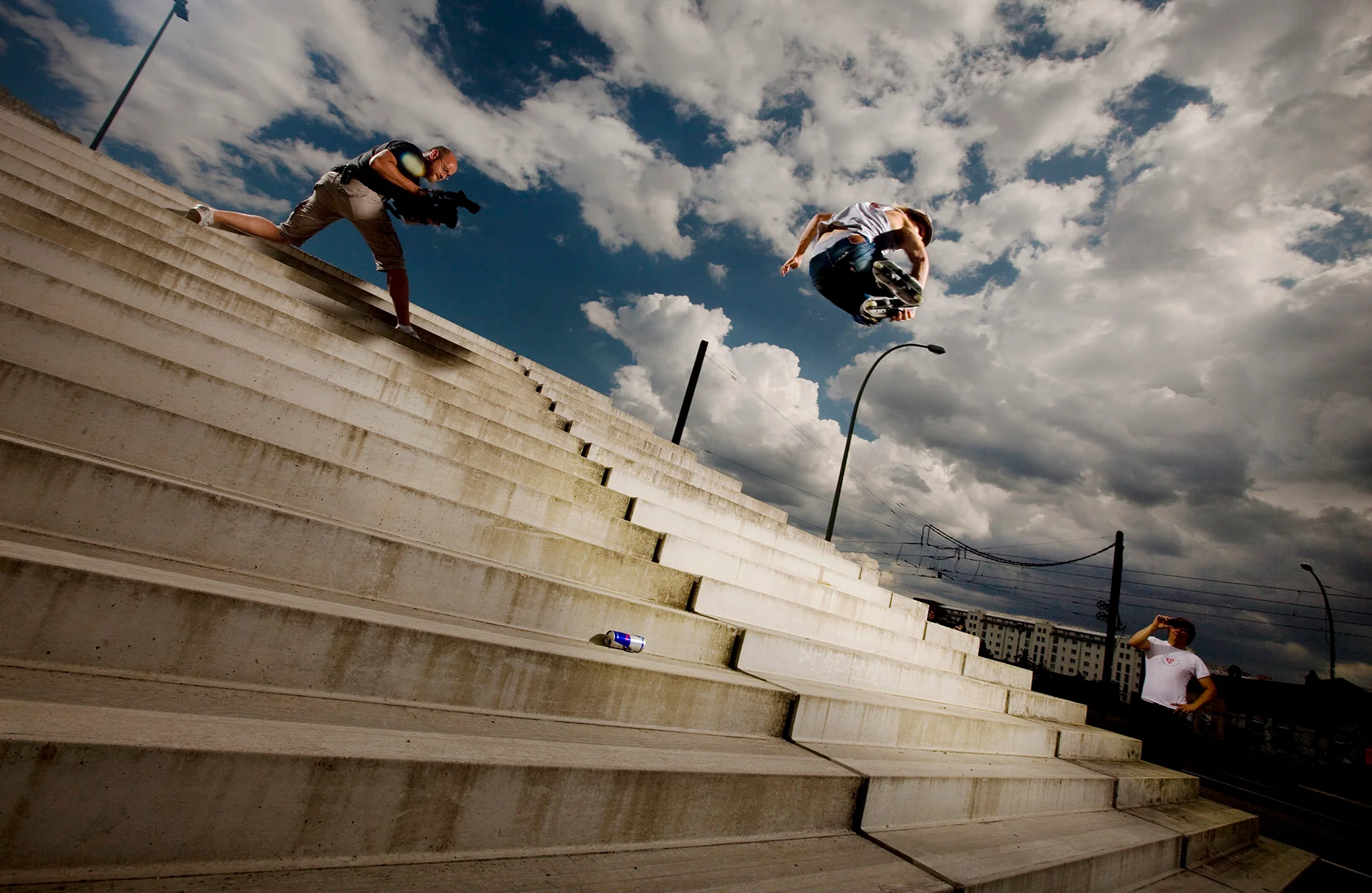Der inline-skater Stefan Horngacher springt am Berliner Velodrom mit seinen inline skate's viele Beton- Treppenstufen herunter.. Im Hintergrund nur Betontreppen und blauer Himmel mit weissen Wolken. Produziert für Red Bull.
