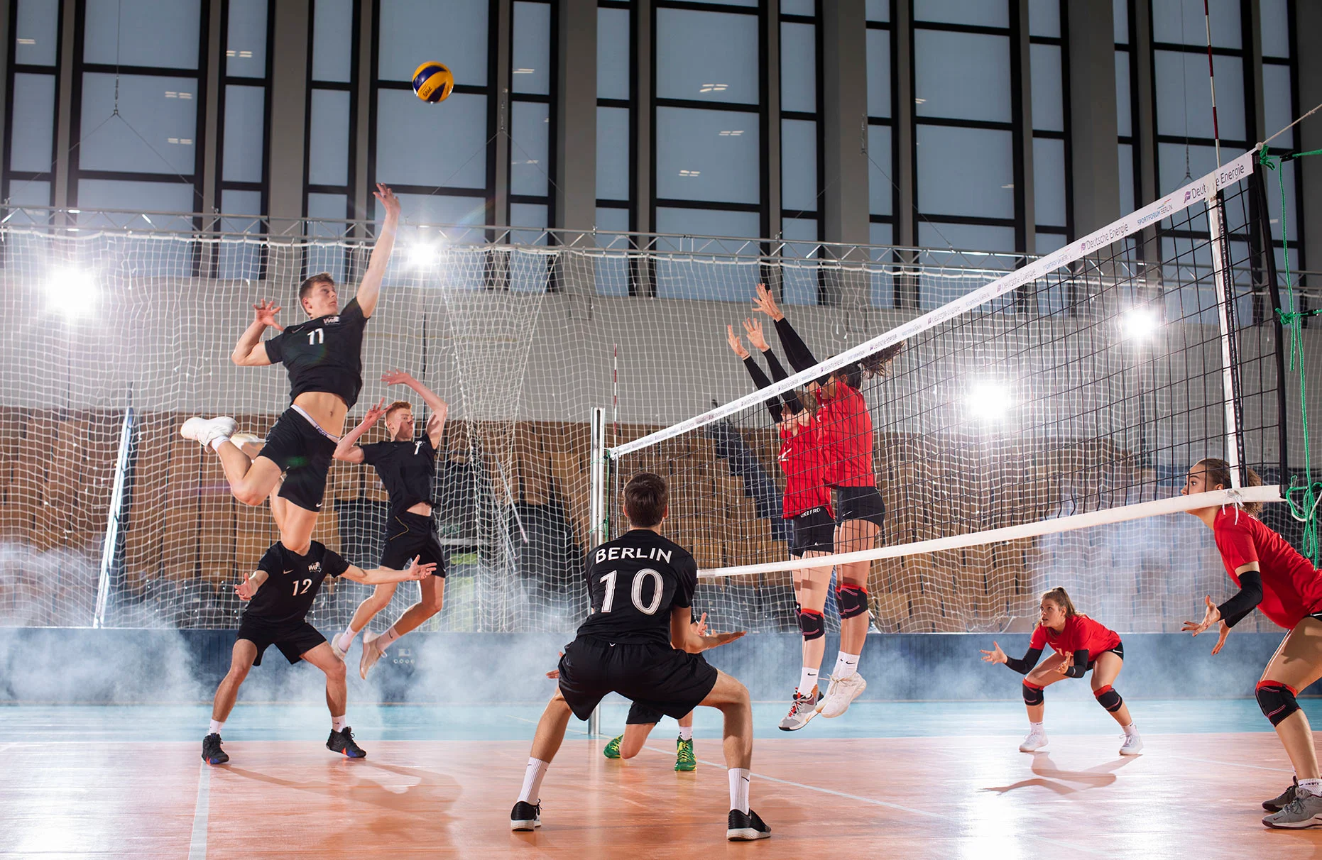 Ein U18 Volleyball Frauen-Team spielt Volleyball in ihrer Trainings- Sporthalle. Viel Blitzlicht- Gegenlicht und Nebel. Eine Freie Arbeit.