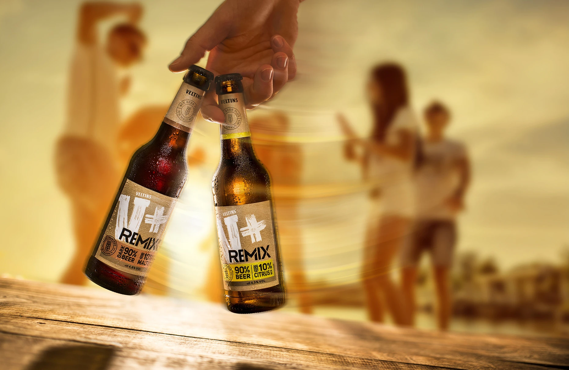 Eine Hand hält hängend zwei Veltins Vplus Flaschen. Der Effekt derBewegungsunschärfe dabei ist mit digitaler Hilfe entstanden. Der Hintergrund mit DStrand und feiernden Freunden ist ein stock Archiv Foto. Produziert für die PR-Agentur Schröder und Schömbs PR aus Berlin.