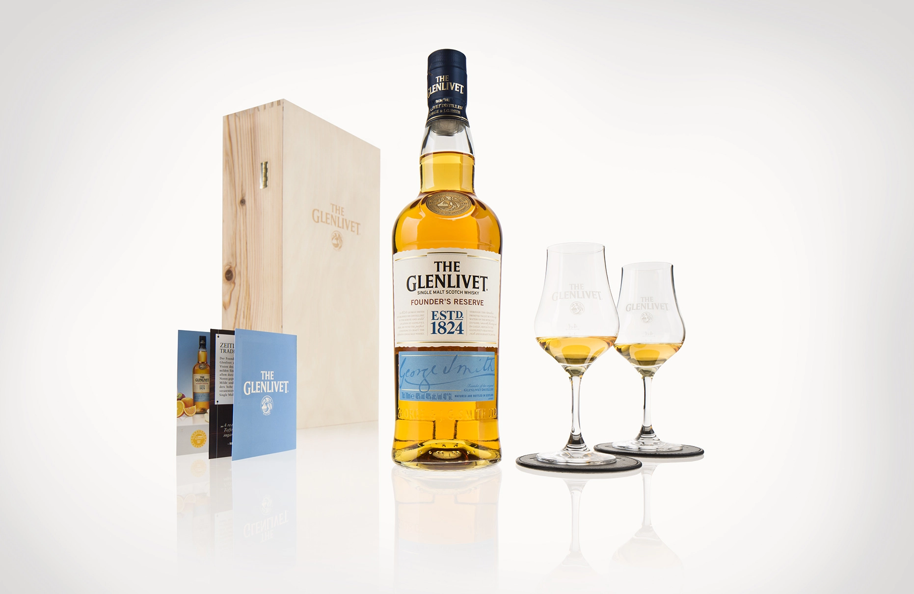 Fotografiert auf einem Leuchttisch steht eine Komposition aus Glenlivet Flasche, gefüllten Gläsern und Karton. Die Gegenstände spiegeln sich leicht im weissen Untergrund. Produziert für die PR-Agentur Schröder und Schömbs PR aus Berlin.